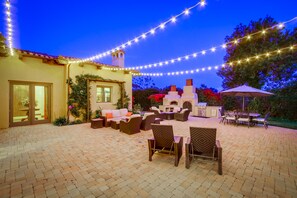 courtyard with market lights and outdoor fireplace and pizza oven