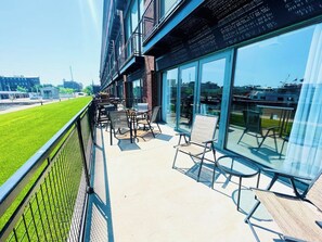 A wide patio with ample seating and stunning harbor views. The patio features comfortable chairs and a table, ideal for relaxing or dining outdoors.