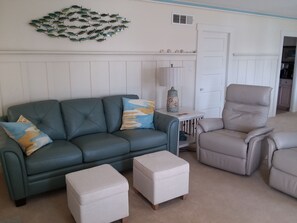 Comfy leather couch and power recliners in a beachy living room, ocean views.