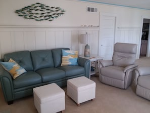 Comfy leather couch and power recliners in a beachy living room, ocean views.
