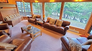The living room has large picture windows with a tree backdrop.