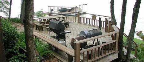 Deck is shaded by umbrella of trees with tiki lights I outdoor dining furniture