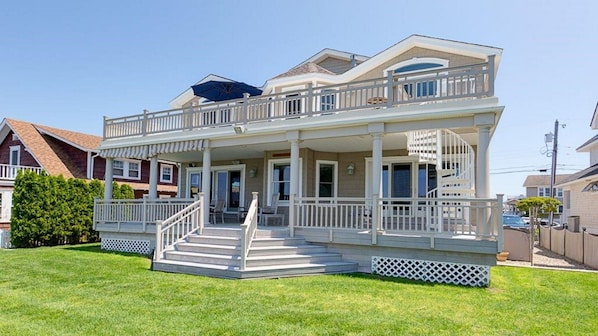 Back of house. Covered downstairs porch, umbrella on upper deck. 