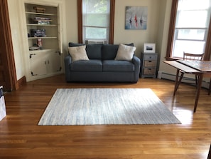 Den connected to living room, with sleeping sofa