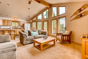 The large living room has vaulted ceilings and floor-to-ceiling windows.