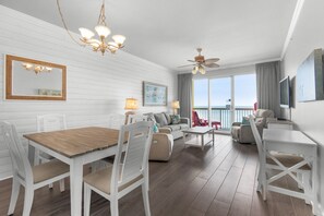Living Room - Luxury and comfort meet in this beachfront living room with plush seating, a large flat-screen TV, and stunning ocean views through floor-to-ceiling windows. 