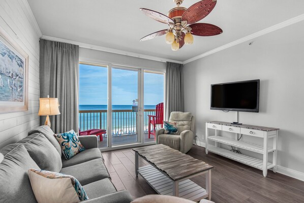 Living Room - Luxury and comfort meet in this beachfront living room with plush seating, a large flat-screen TV, and stunning ocean views through floor-to-ceiling windows. 