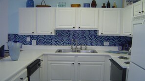 Plenty of countertop space for cooking. Blue glass backsplash. Nicely decorated