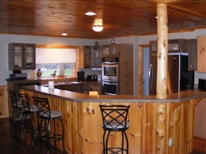 Kitchen with split level counter ad stools. Kithcen looks into great room