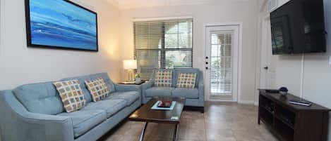 Stylish open-plan living space with sofas, Smart TV, fan and door to the patio