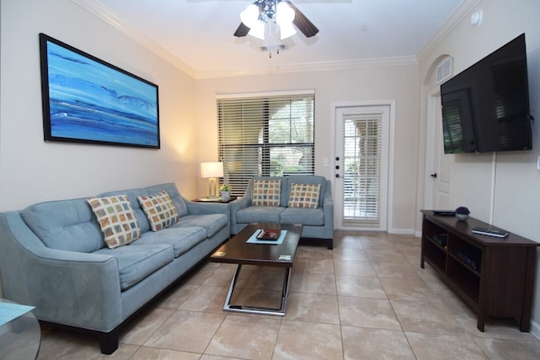 Stylish open-plan living space with sofas, Smart TV, fan and door to the patio