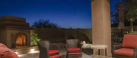The outdoor living room includes a comfy couch and chairs with a ceiling fan.
