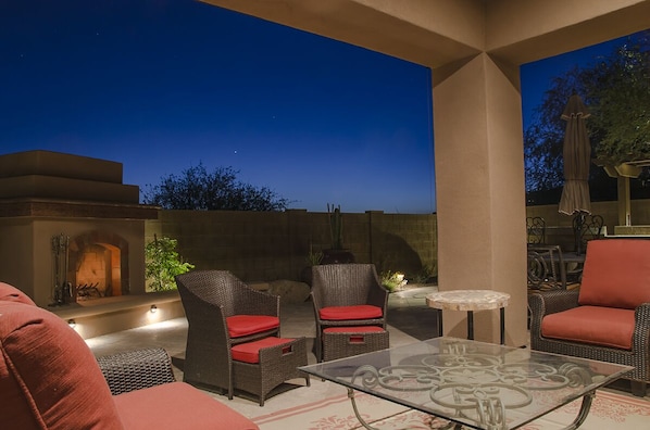 The outdoor living area includes a comfy couch and chairs with a ceiling fan