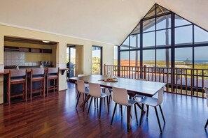 Gather around the spacious dining table while taking in spectacular sunsets through the floor-to-ceiling glass windows. The perfect setting for memorable meals.