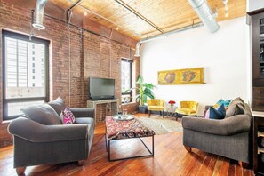 Large sun flooded living area with TV and large windows 