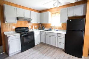 Fully stocked kitchen with pots, pans, appliances, plates, and silverware.