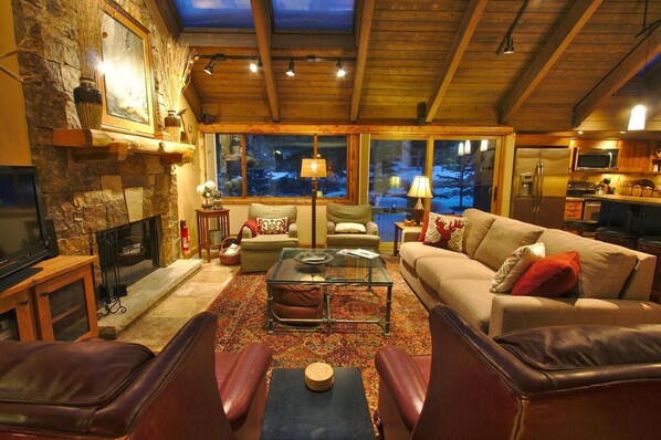 The Great Room that has the feel of the outdoors with large windows skylights in the vaulted timber ceiling and wood burning fireplace 