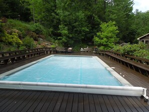 View of heated  pool & pool deck with perimeter bench seating from Pool House. 