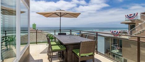 Expansive ocean views from upper deck, with large dining table and BBQ