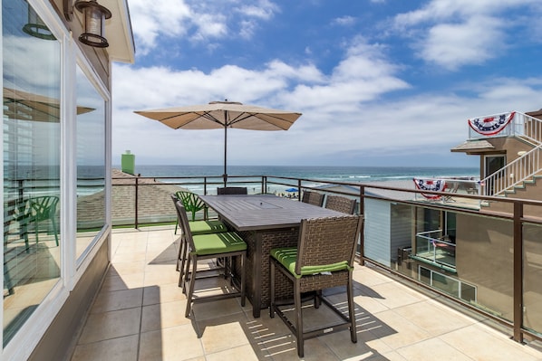 Expansive ocean views from upper deck, with large dining table and BBQ