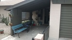 Covered patio in front of house with cozy seating.
