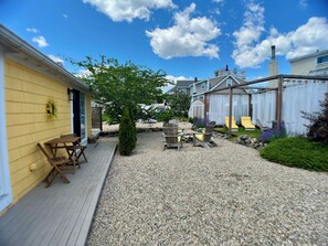 Private outdoor space with lounge chairs, gazebo, dining table and fire pit.