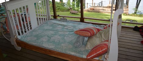 Queen-size hanging bed on spacious  porch is wonderful for napping and reading.