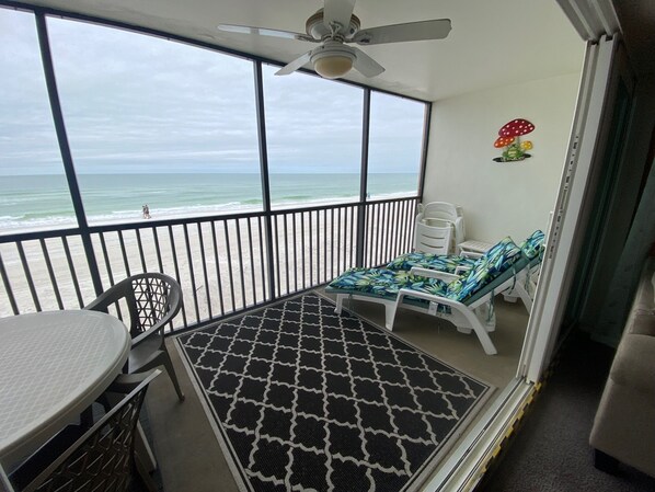 Screened in Lanai with cushioned lounge chairs and eating area with gulf view.