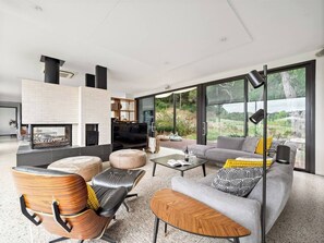 Relax in plush seating by the fireplace, with floor-to-ceiling glass doors leading to the garden.