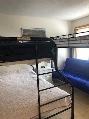 Bunk Room (1 Queen Bed, 2 Twin beds, and Futon) - smart TV on the wall.