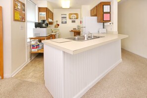 Fully stocked kitchen with dishes, cookware, microwave, coffee maker, oven, etc