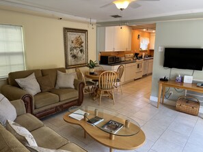 Living room with flat-screen TV, dining area and view into galley kitchen