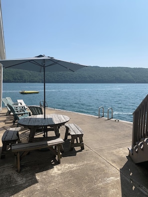 South side waterfront level with lounge chair, adirondacks, hot tub and table