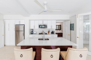 Discover a generously sized and fully equipped kitchen, featuring a stylish island counter accompanied by sleek, modern design bar stools