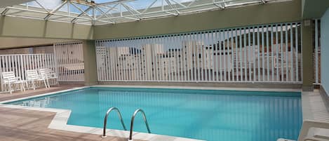 Deliciosa piscina aquecida coberta com teto de vidro na cobertura do prédio 