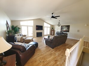 Main level great room with TV, plenty of seating, dining area, and fireplace.