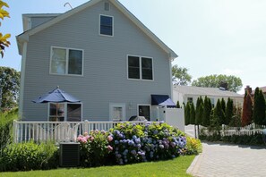 Back of house with grill and outdoor shower. Basketball hoop in driveway