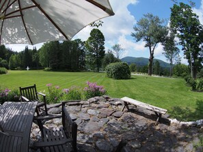 View south from slate patio towards swimming pond fountain, lawn, and mountains.