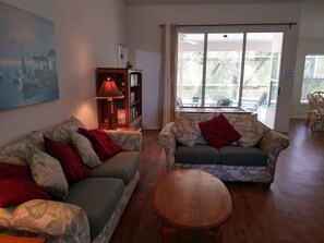 Comfortable living room overlooks pool deck and woodland conservation