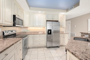 Bright, modern, fully-equipped kitchen with granite countertops and stainless steel appliances.