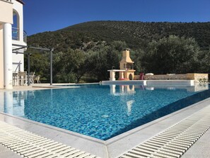 View over the swimming pool towards the outdoor BBQ & sunbed area.