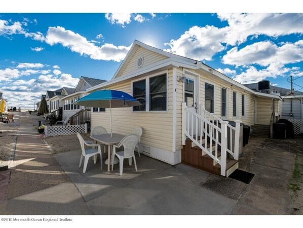 front patio with table and wooden Adirondack chairs set in the sand