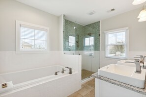 Stunning large primary bath with stand-up shower featuring floor-to-ceiling tile and separate soaker tub.   Tons of natural light.