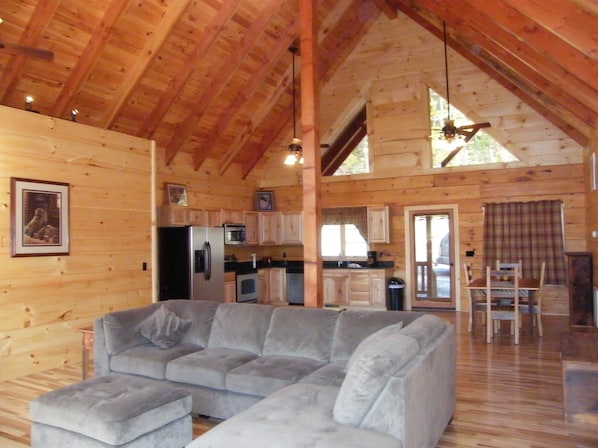 Great room with exposed beams, hickory floors and a nice sectional sofa to relax