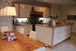 Kitchen/Dining Room with 7 Ring Hob, 3 Ovens and Large Reclaimed Wooden Table overlooking gardens