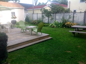 Back yard with privacy fence and picnic table is a tree shaded area. And grill