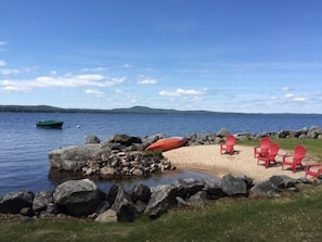 Sandy swimming cove with adirondack chairs, kayaks and canoe