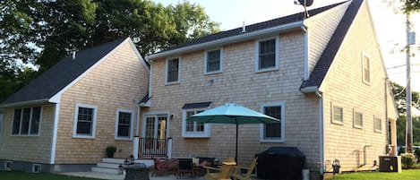 Rear view of the house with deck, patio, grill, adirondacks,two tables 12 seats.