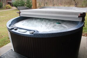 Hot tub located outside with mountain and water views