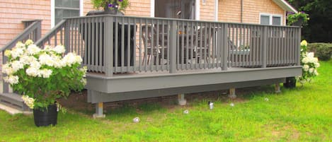 Side of home with large deck and French doors, couch and dining table